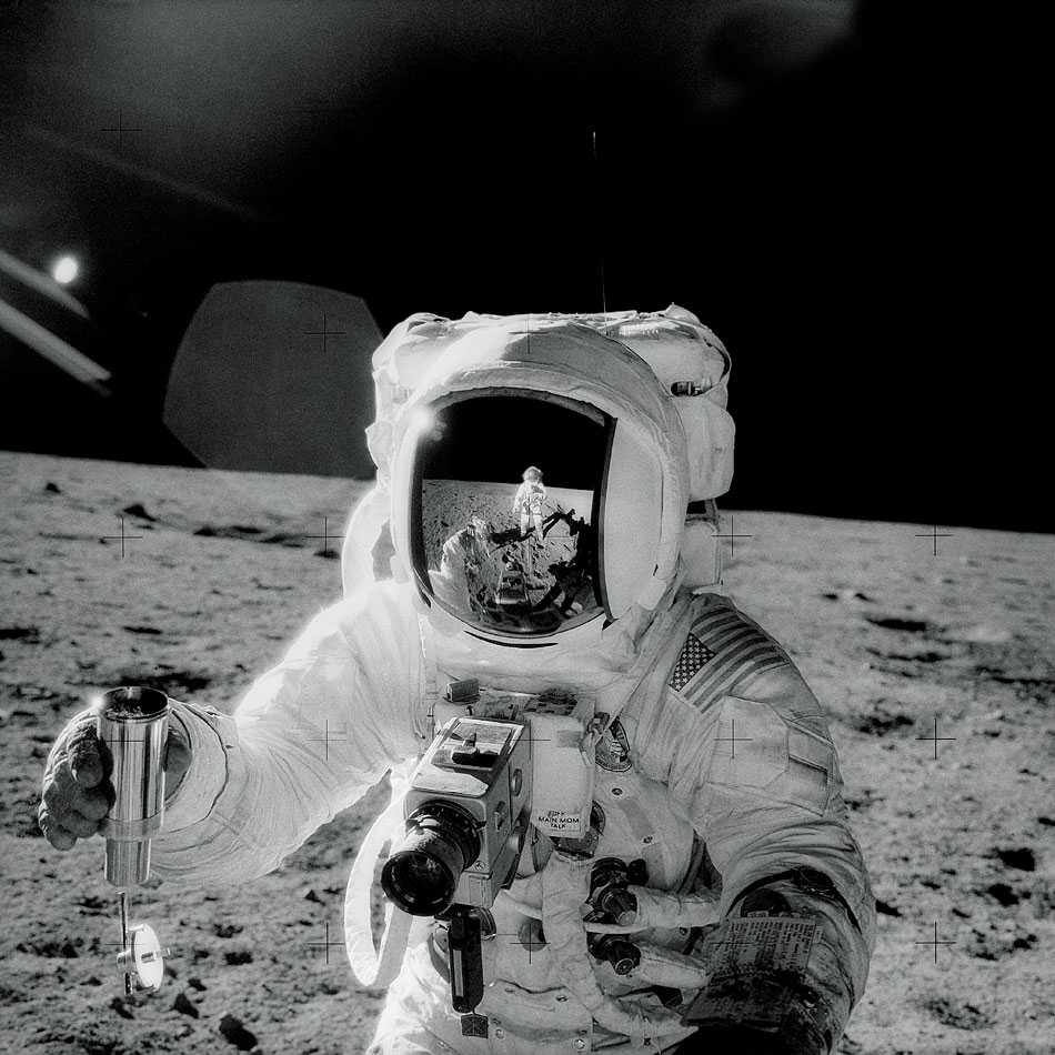 a black and white photo of astronaut Alan Bean collecting lunar soil.